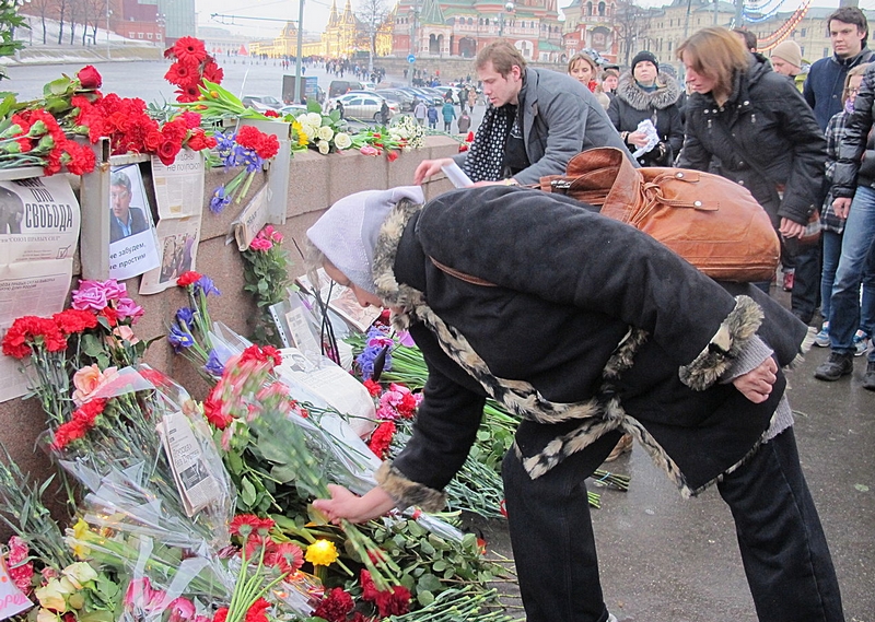 bloemen en een rij bezoekers bij de moordplaats