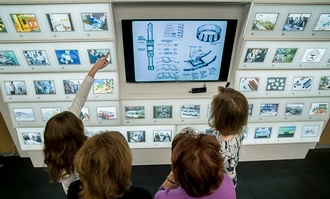 bezoekers kijken naar een panel met afbeeldingen uit de expositie