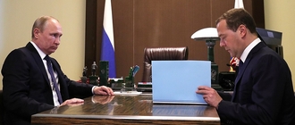 Poetin en Medvedev aan weerzijden achter een bureau